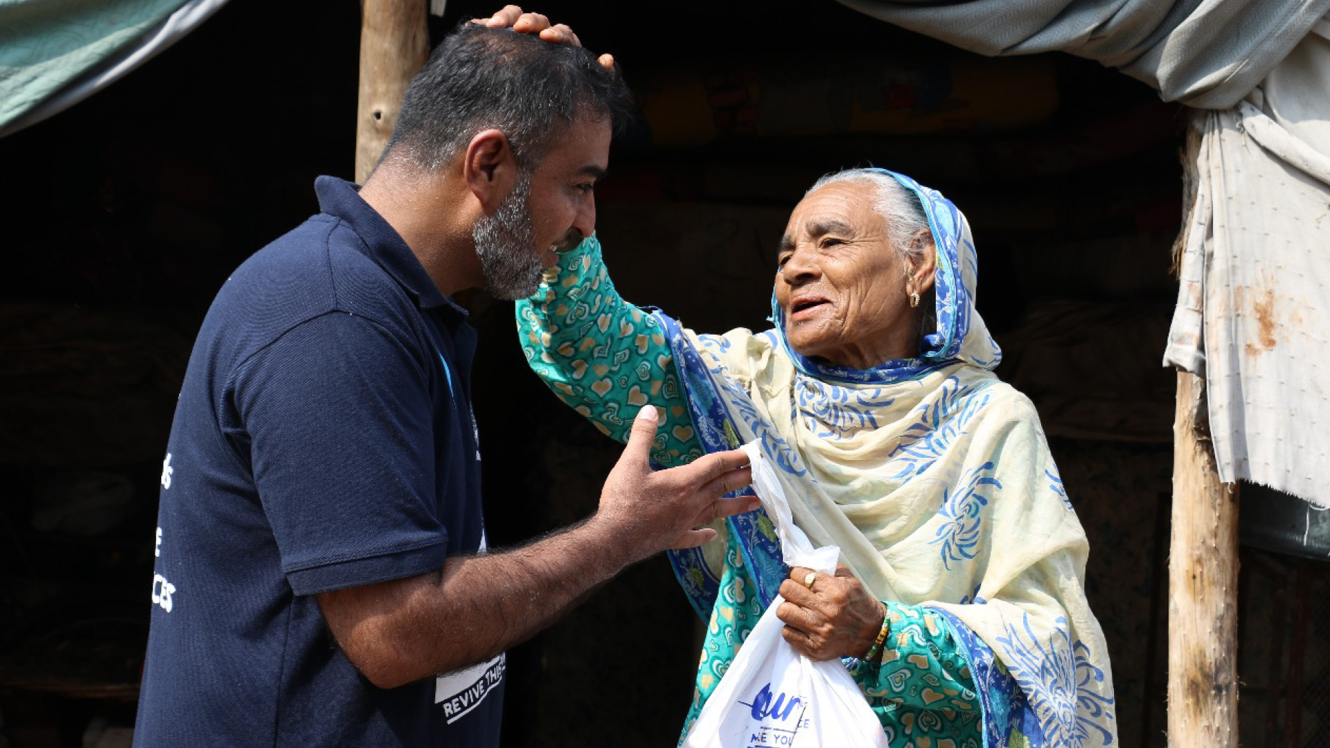 Un humanitaire de Muslim Hands remet un colis de viande de sacrifice à une femme âgée.